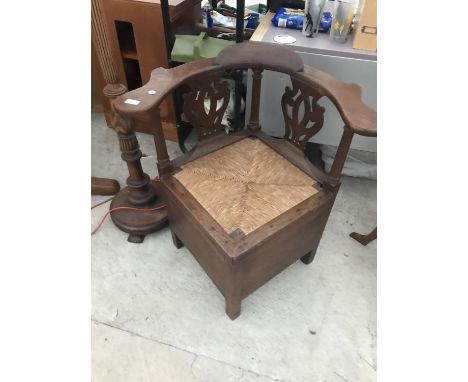 AN OAK CORNER COMMODE WITH FRETWORK BACK AND RUSH SEAT 