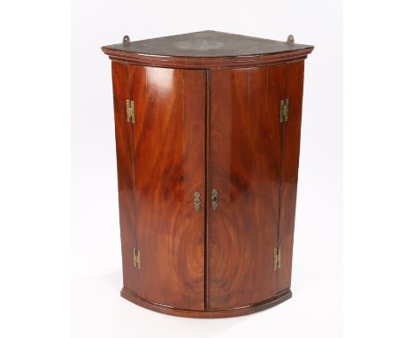 George III mahogany hanging corner cabinet, the cornice above the bow front doors enclosing shelves, 69cm x 48cm x 97cm