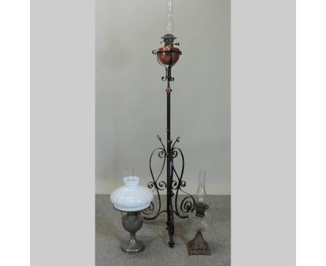 An oil lamp, with a glass reservoir, together with another, with a white glass shade, and a wrought iron standard oil lamp, 1