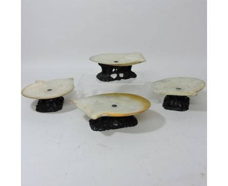 A collection of Chinese mother of pearl dishes, on carved hardwood stands, 5cm tall