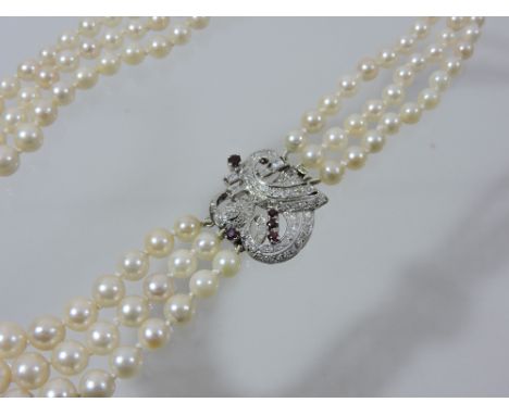 A cultured pearl necklace, having three rows of graduated pearls, with a multi diamond and four ruby set platinum clasp of sc