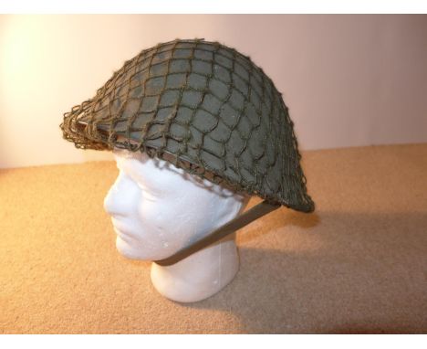 A BRITISH ARMY STEEL HELMET WITH LINING AND NET COVER TOGETHER WITH A CAMOFLAGE COVER 