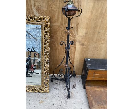 A DECORATIVE BRASS AND COPPER OIL LAMP ON A TALL DECORATIVE BLACK CAST IRON METAL STAND (H:137CM) 