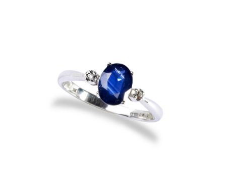 A SAPPHIRE AND DIAMOND RING OVAL the oval cut sapphire set between two round cut diamonds on a white gold band Marked '750' &