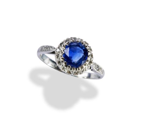 A SAPPHIRE AND DIAMOND CLUSTER RING  the circular mixed cut, within a bezel of sixteen eight-cut diamonds above a pierced gal