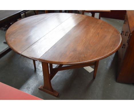 An Ercol elm gate leg round dining table 140 x 127 x 72cm