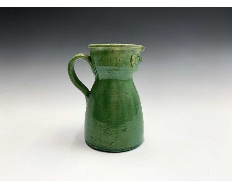 A circa 1900 tin glazed green folk art, face mask jug, height 20cm.