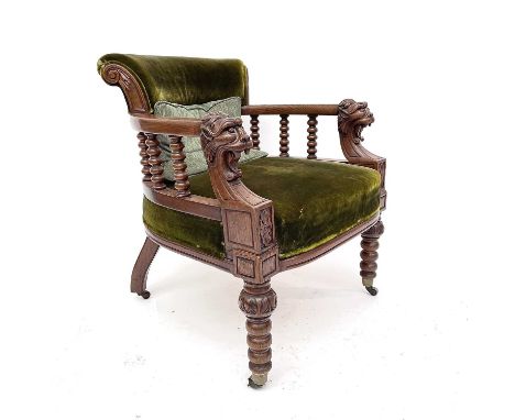 A Victorian oak upholstered tub chair skillfully carved with lion masks, flower roundels, bobbin turned bannisters with bobbi