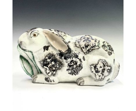 A Staffordshire large pottery figure of a rabbit, modelled nibbling on a leaf, with black and white markings, length 26cm.Pro