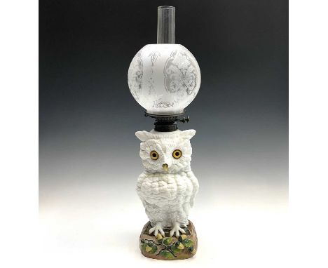 A large German porcelain owl oil lamp, late 19th century, with glass inset eyes, on an acorn moulded base, height of owl 34.5