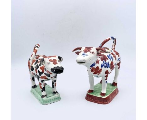 A Staffordshire cow creamer, early 19th century, with black and red sponged decoration, on green mound base, length 17cm, tog