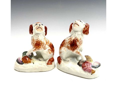 A pair of Staffordshire pottery figures of spaniels, each seated and with its front paw upon a pheasant, height 10.5cm. Alan 