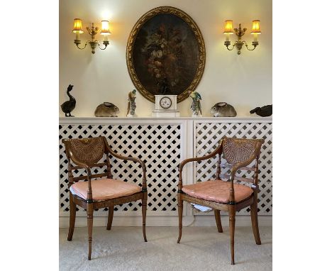 A pair of Sheraton style painted satinwood elbow chairs, 20th century, with caned seats and backs on turned, slightly splay f