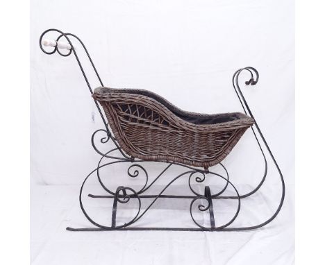 A wicker sled on scrolled wrought-iron base 