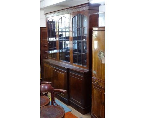 A mahogany 2-section library bookcase, in Chippendale style, having 3 arched lattice-glazed doors, on a break-front cupboard 