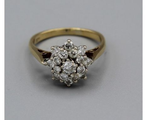 A diamond cluster ring in yellow metal, stamped 18ct. Gross weight approx 3.9gm, size L. Set with round brilliant cut diamond