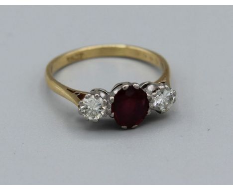 An 18ct stamped yellow metal dress ring featuring a central ruby of 8 x 5mm approx and two diamonds, round brilliant cut appr