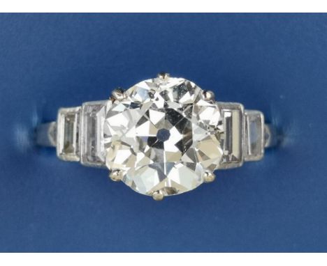 An art deco diamond solitaire ring, the claw set old cut stone weighing approximately 2.3 carats, flanked by four small step 