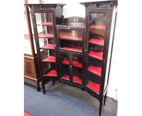 AN EDWARDIAN EBONISED DISPLAY CABINETwith an arrangement of glazed doors, the two taller doors canted, and with wide overhang