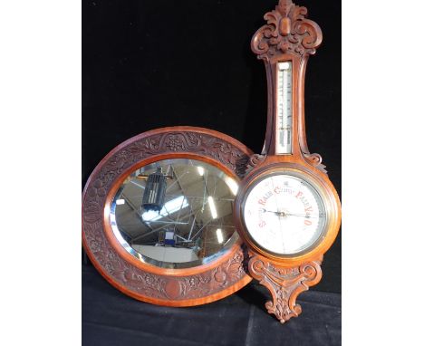 A CARVED WALNUT FRAMED OVAL MIRROR55.5 x 65.5cm, and a carved oak aneroid barometer by Vincent, Weymouth (2)