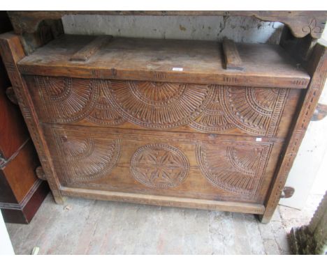Oriental cedar chest of thick plank construction, with a hinged lid above a carved front on slab end supports, 49.25ins wideA