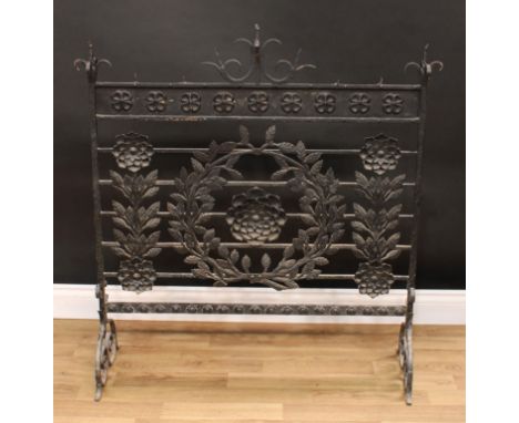 A large Arts and Crafts wrought iron country house firescreen, scroll finials above a deep frieze applied with a row of rose 