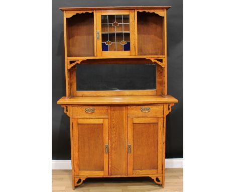 An Arts &amp; Crafts oak side cabinet, shallow outswept cornice above a central Art Nouveau design glazed door enclosing a sh