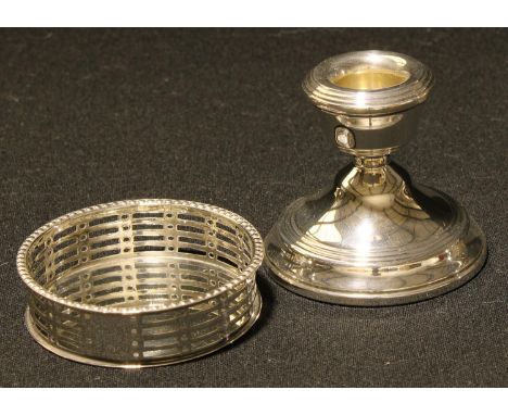 A silver coaster, pierced gallery, 8cm diameter, Chester 1907, 49g; a silver boudoir candlestick, hollow filled, 7cm, Birming