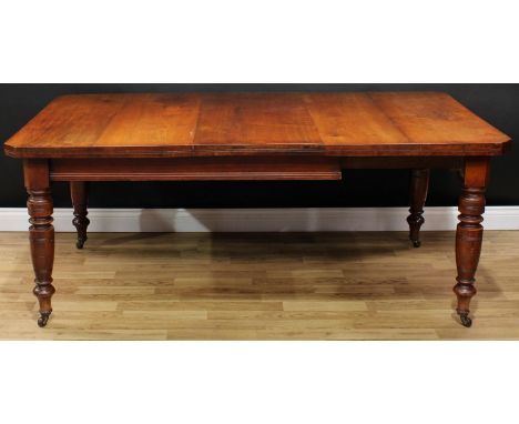 A late Victorian walnut extending dining table, chamfered rectangular top with one additional leaf, above a deep frieze with 