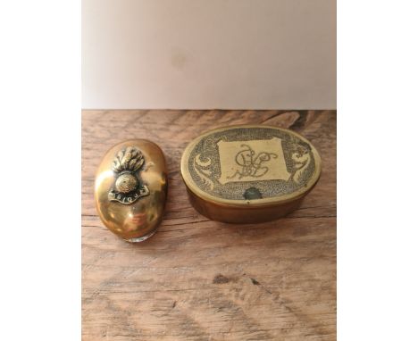 A brass snuff box, hinged, 1917 penny and UBIQUE cap badge and a brass tobacco box of oval shape, initials engraved on lid an