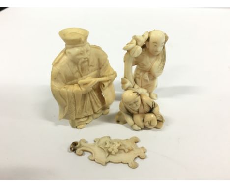 An early 20th century signed carved ivory Netsuke modelled as a Scribe together with two miniature carved ivory figures and a