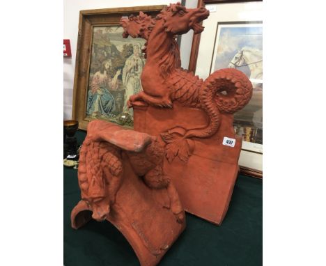 A terracotta roof finial modelled as a pair of grotesque sea horses together with a roof corbel with winged animal mount.