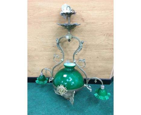 A large hanging brass and green glass shade oil lamp, decorated with winged female figures and face masks with twin small gre