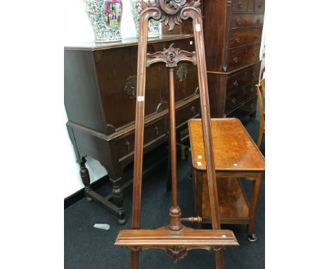 A large mahogany decorative adjustable easel resting on scrolled feet.