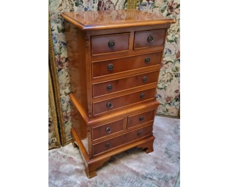 A small reproduction yew chest on stand, the crossbanded oversailing top flanked by fluted columns holding two short above fo