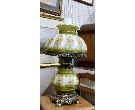 A vintage oil lamp, cast metal mounts with transfer printed glass reservoir and shade in green and white, frosted glass chimn