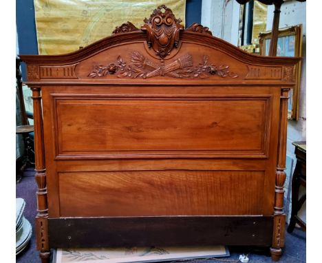 A French walnut double bed headboard, carved with crossed quivers, torch and foliage, 150cm wide 