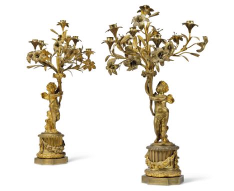 A pair of French gilt-bronze six-light figural candelabra, late 19th / early 20th century, each modelled as winged putto hold