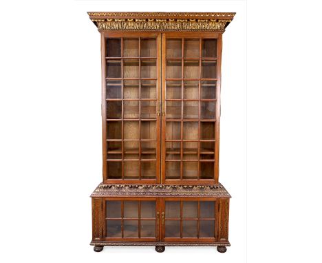 An English oak and parcel gilt Pepys type bookcase, first quarter 20th century, with acanthus leaf carvings and four glazed d