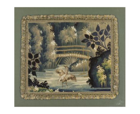 A Flemish verdure tapestry fragment, 17th century, woven in wools and silks, depicting a heron before a bridge in a river wit