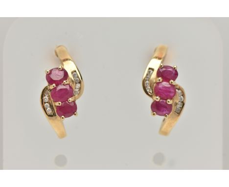 A PAIR OF 9CT GOLD RUBY AND DIAMOND EARRINGS, each designed as a diagonal row of three oval rubies with curved lines from eac