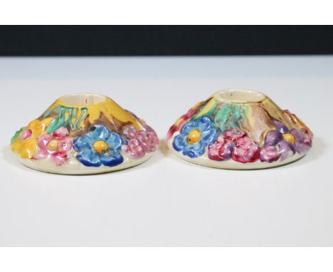 Pair of Clarice Cliff taper candlestick holders having moulded floral details and hand painted details. Stamped mark to base,