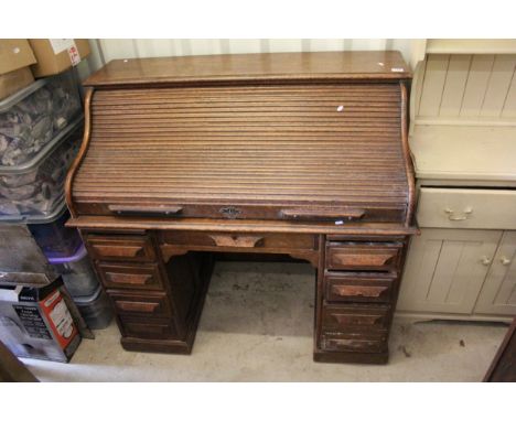 Early 20th century 'The Victoria Desk' oak roll top tambour shutter desk with centre drawer above kneehole and eight side dra