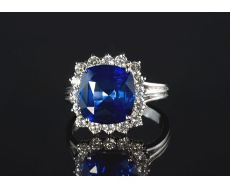 A fine 18ct white gold, sapphire and diamond cluster ring, the 6.45ct cushion cut sapphire within a border of sixteen brillia