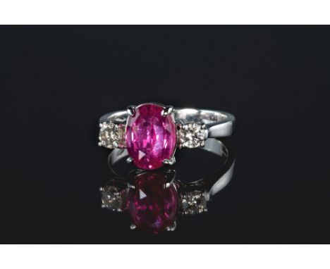 An 18ct white gold, pink sapphire and diamond three stone ring, the oval cut 2.60ct sapphire flanked by two brilliant cut dia