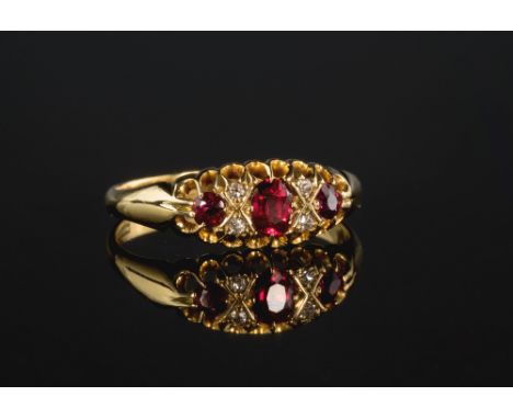 An Edwardian 18ct yellow gold, ruby and diamond five stone ring, the central oval cut ruby flanked by two round cut rubies an