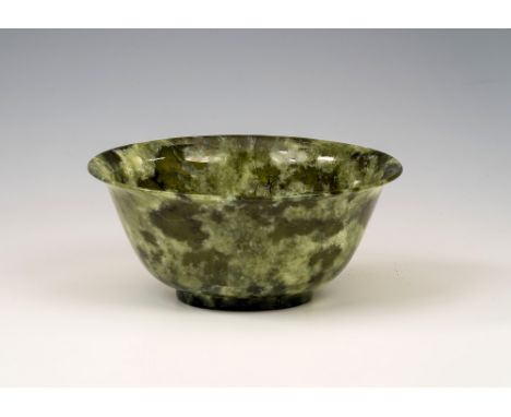 A Chinese carved spinach jade bowl, 20th century, with deep rounded sides rising to a flaring rim from a short circular foot,