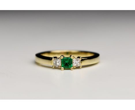 An 18ct yellow gold, emerald and diamond three stone ring, the square cut emerald flanked by a pair of princess cut diamonds,