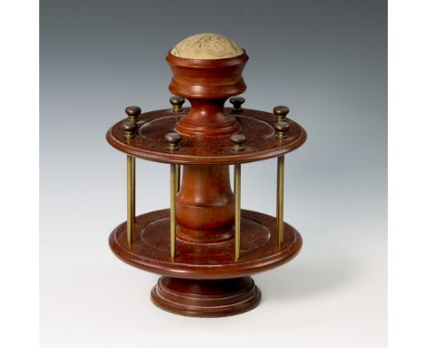 A 19th century treen cotton reel stand, of circular design, having eight cotton reel holding rods, surmounted by a pin cushio
