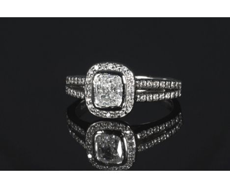 A palladium and diamond cluster ring, the 0.71ct cushion cut diamond, GIA cert. F/SI1, in a rub over setting within a halo bo